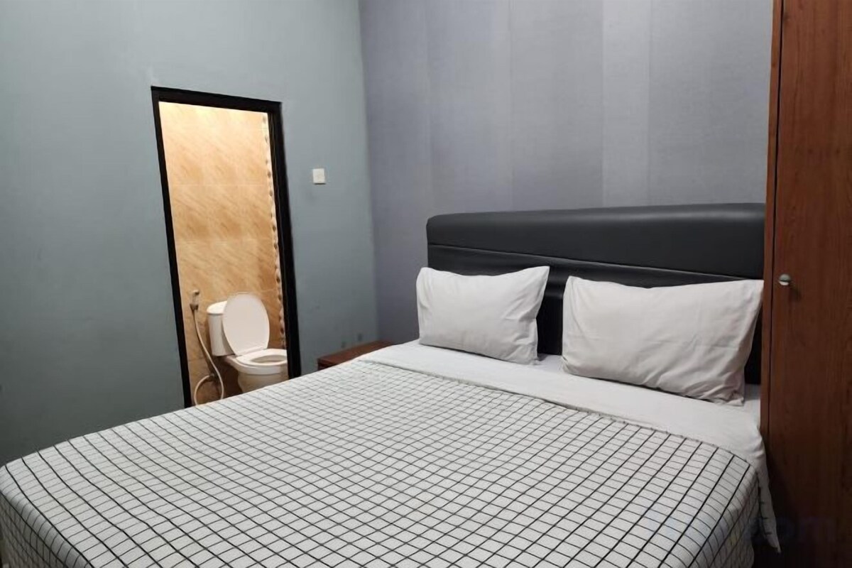 A bedroom with a bed, a door, and a toilet.
