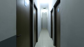 Un pasillo estrecho y bien iluminado con puertas a ambos lados, que conduce a una habitación luminosa al final.