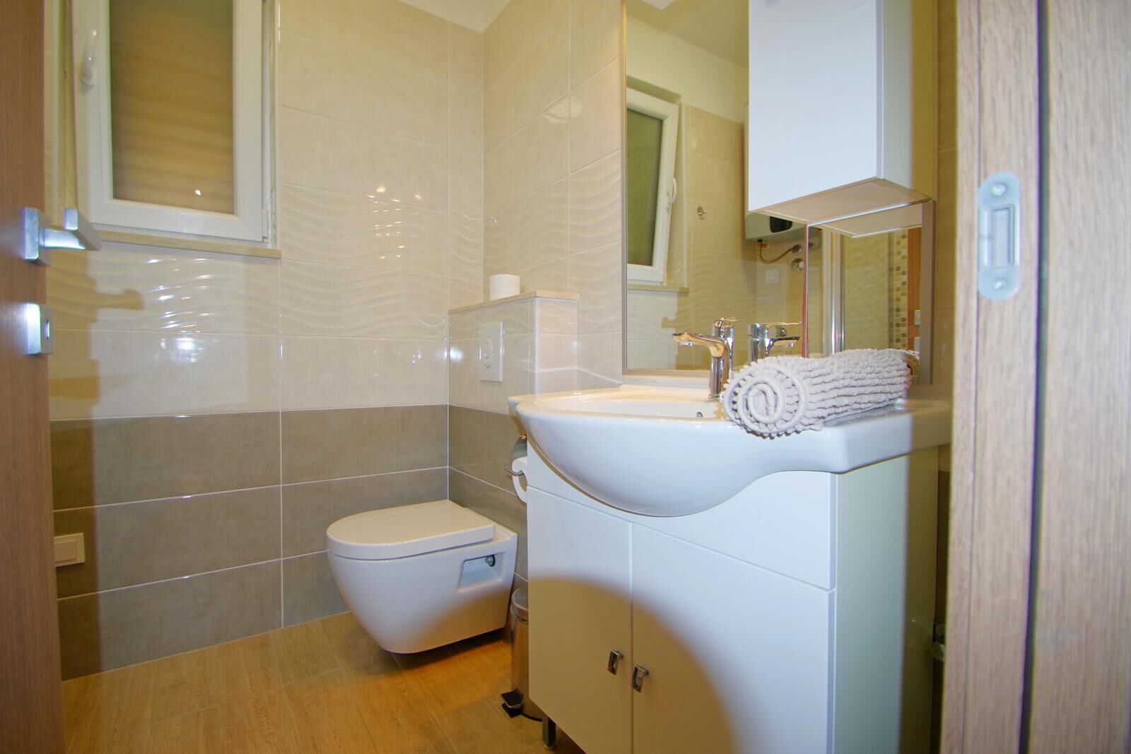 A bathroom with a toilet, sink, mirror, and towel.