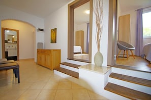 A modern interior with a wooden staircase, a dining area, and a bedroom with a large mirror. - Spacious holiday apartment with big covered terrace in village Valbandon (Valbandon, Fažana)