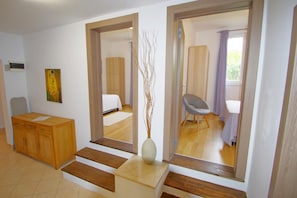 A modern hotel room with a wooden desk, a large mirror, a vase with branches, and a bed with a white bedspread. - Spacious holiday apartment with big covered terrace in village Valbandon (Valbandon, Fažana)
