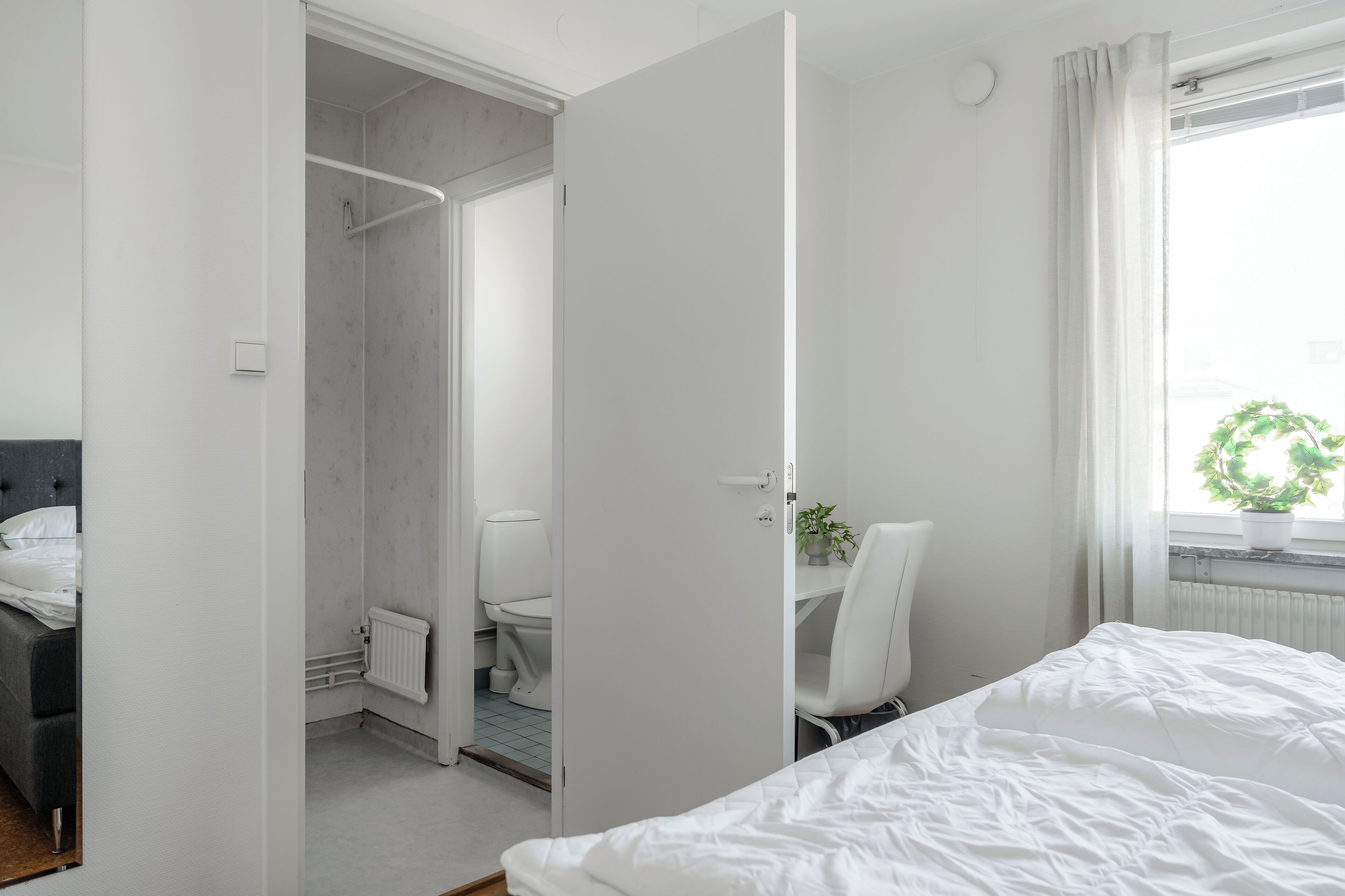 Habitación de hotel moderna con cama, escritorio y zona de ducha.
