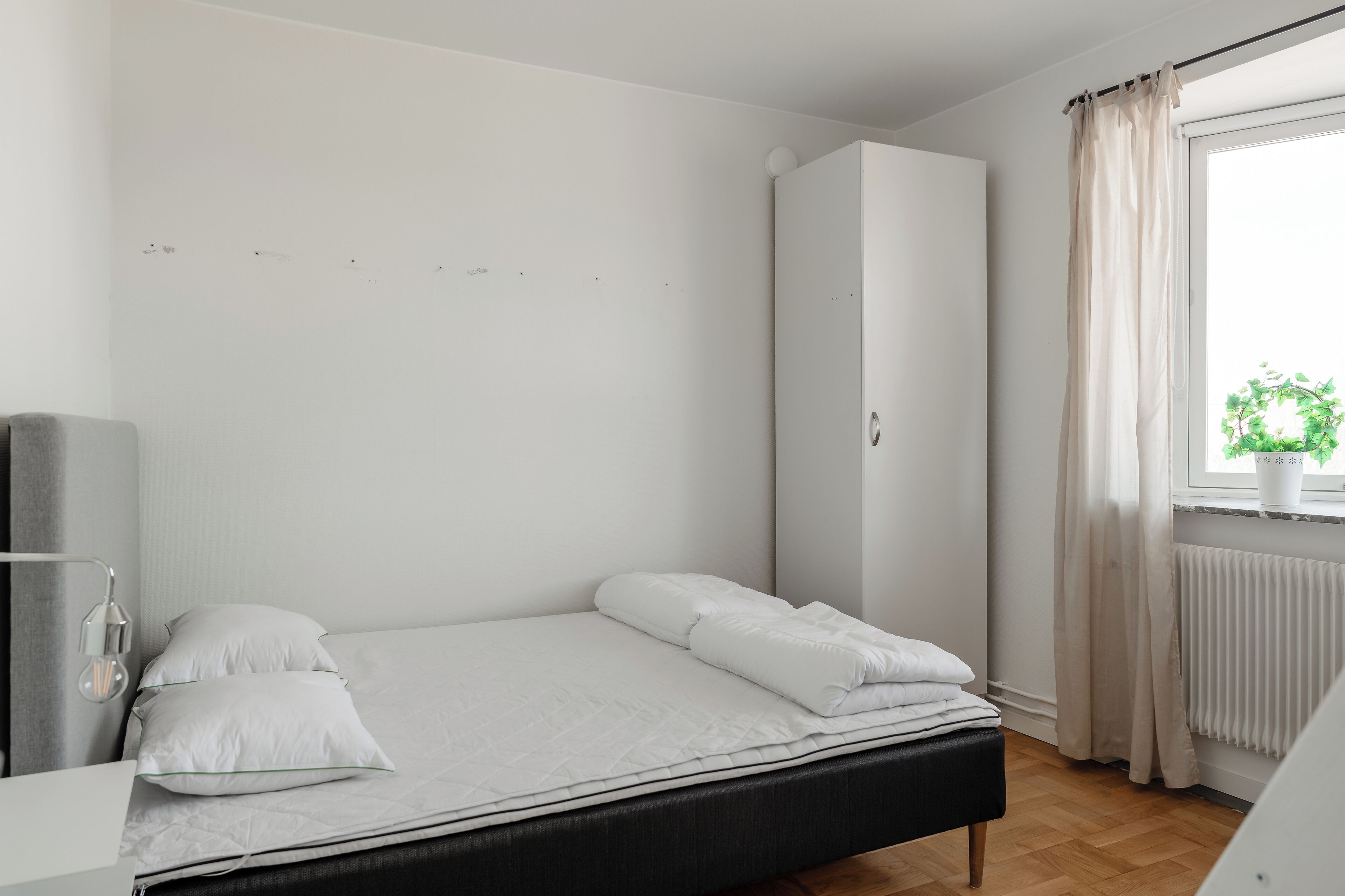 Un dormitorio minimalista con cama, armario y ventana con cortinas.