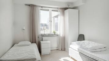 A bedroom with two beds, a desk, and a radiator.