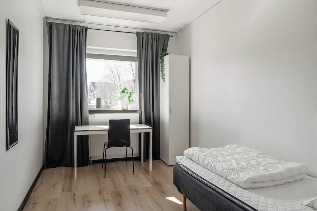 A bedroom with a bed, a desk, and a chair.