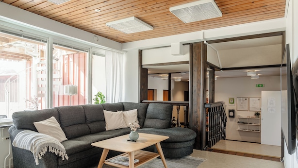 Una sala de estar moderna con un sofá gris, una mesa de centro de madera y vistas a una escalera que da a una zona de cocina.
