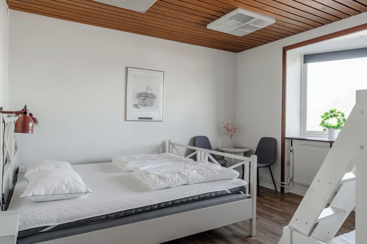 A modern bedroom with a bed, a desk, a chair, and a radiator.