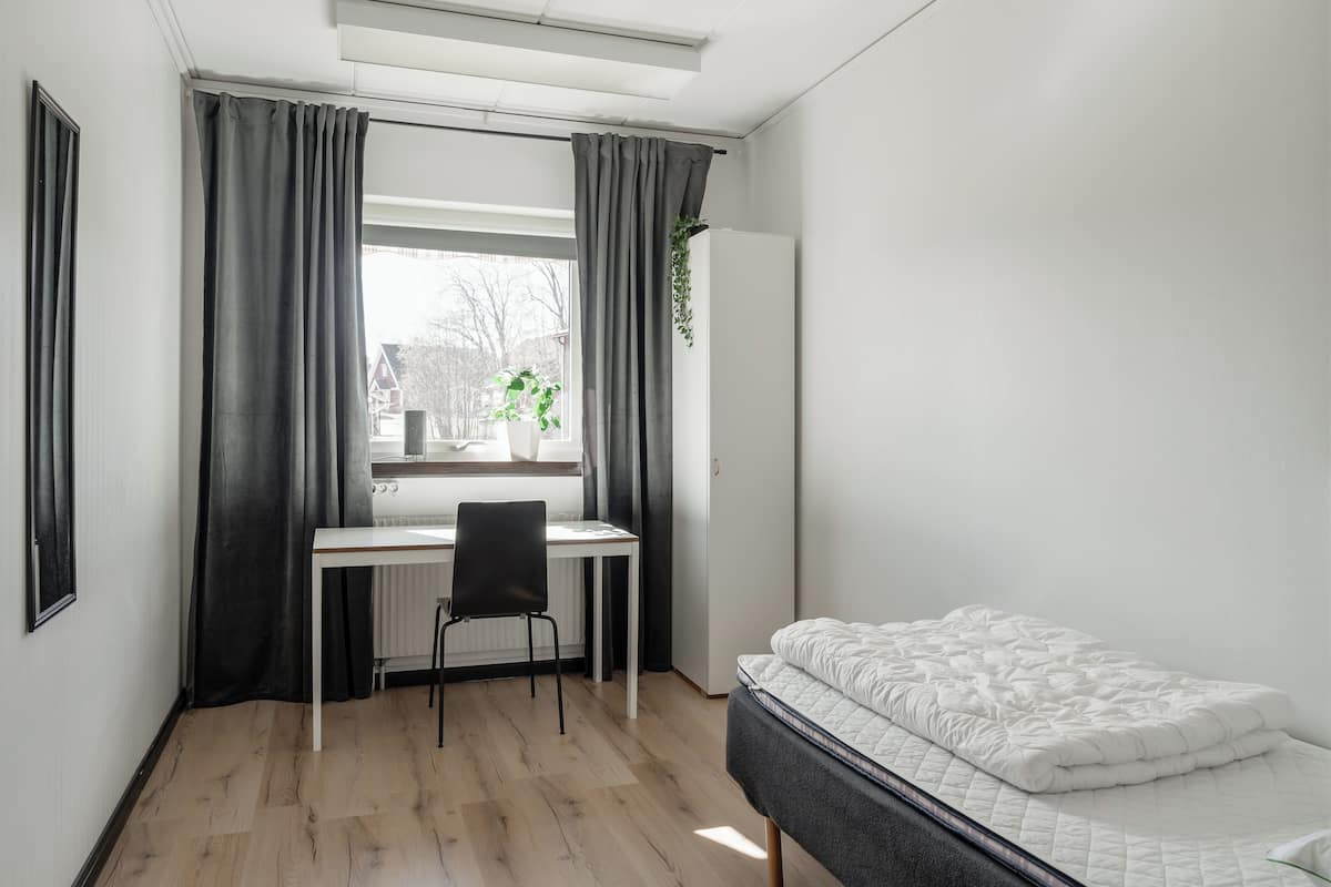 A small, modern bedroom with a bed, a desk, and a chair.