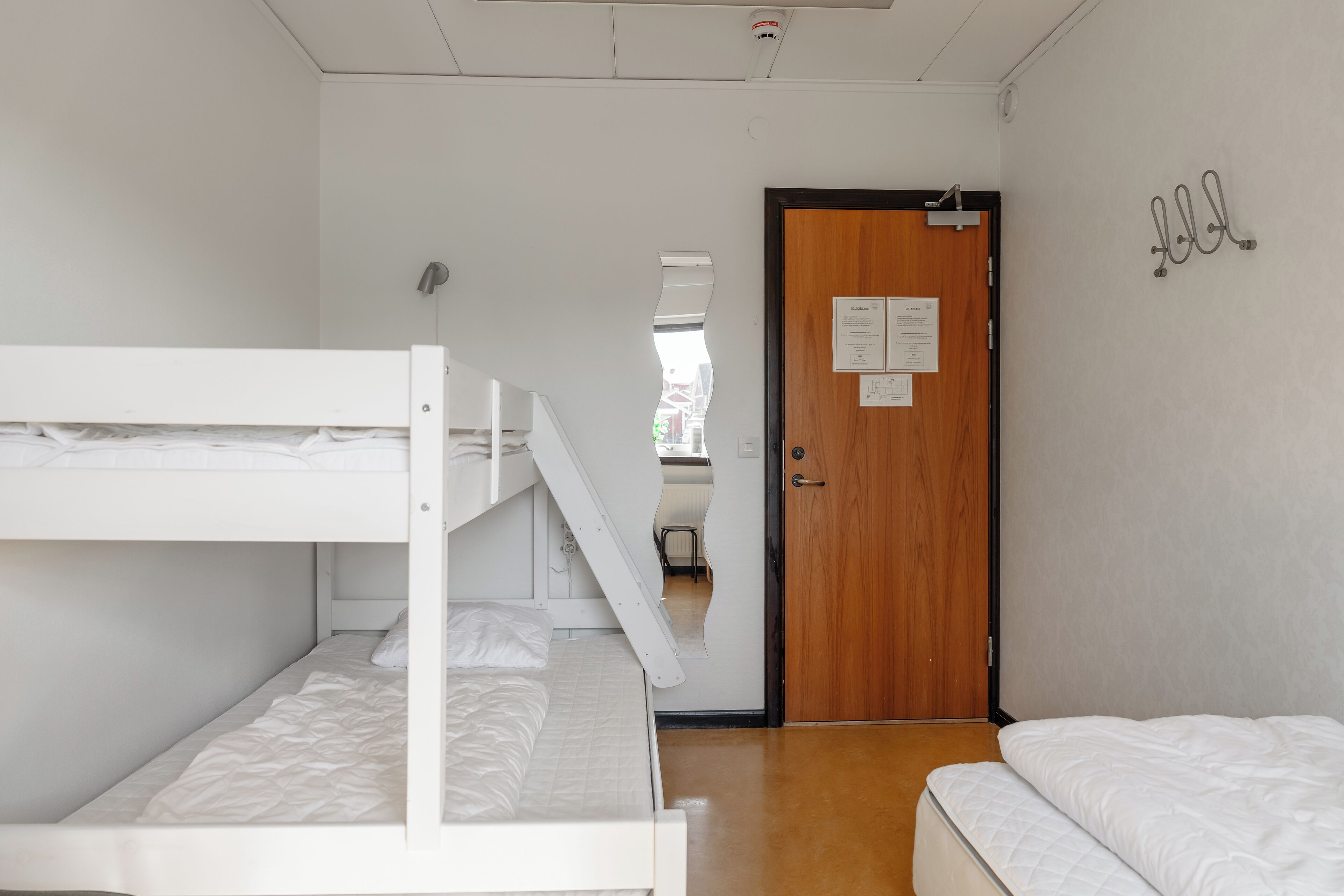 Un dormitorio con literas, una puerta de madera y un espejo pequeño.