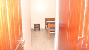 A narrow hallway with a bed and a small bedside table.