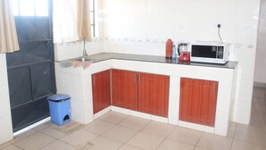 A kitchen with white cabinets, a microwave, and a blue trash bin.