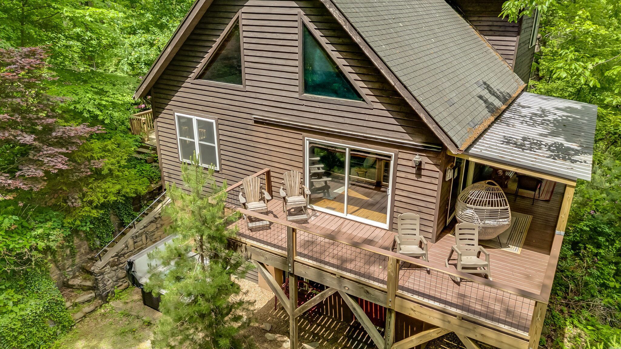 A wooden cabin with a deck, large windows, and a birdcage.