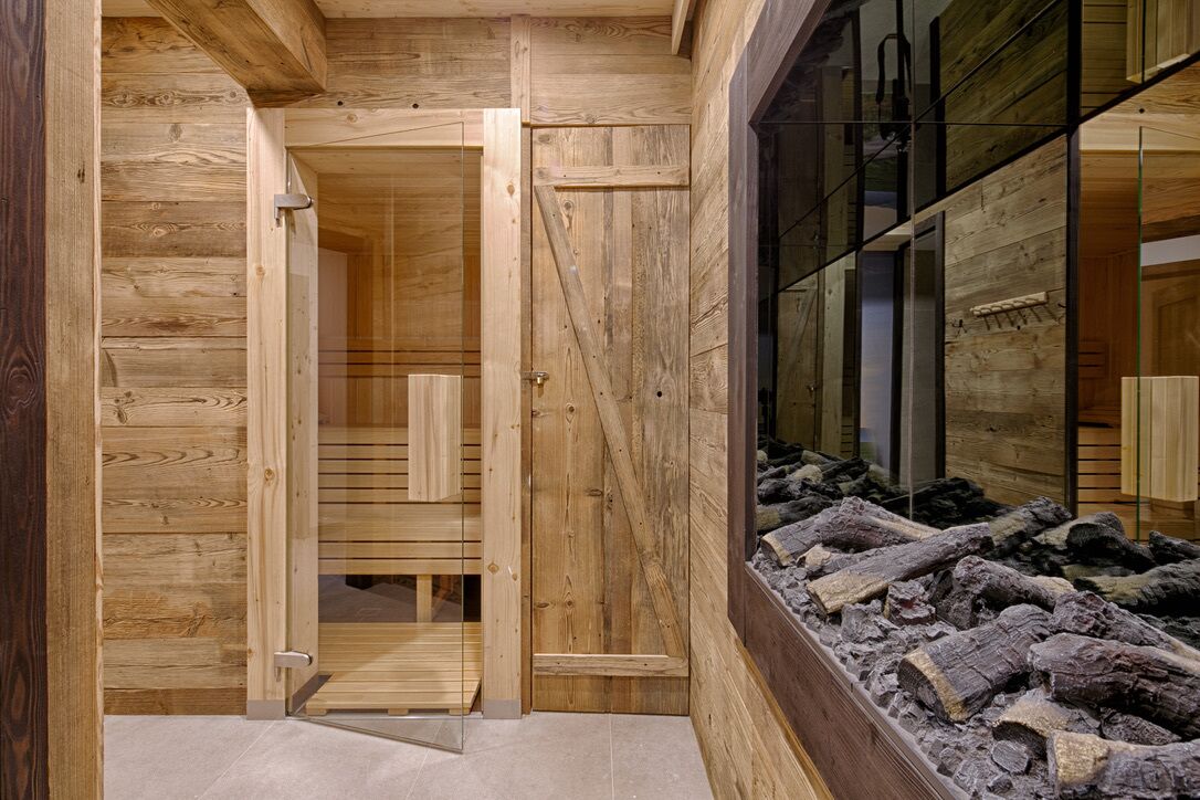 Un intérieur en bois agrémenté d’une cloison en verre, d’un banc en bois et d’une présentation de bûches.