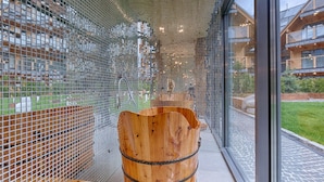 A modern interior with a mosaic wall, wooden barrel seating, and a view of residential buildings. - Goralski Szyk Royal Resort Wellness&SPA (Zakopane)