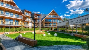 A resort with multiple wooden buildings, a well-maintained lawn, and a clear sky. - Goralski Szyk Royal Resort Wellness&SPA (Zakopane)