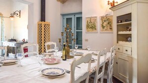 A dining area with a table set for four, white chairs, and a cabinet with decorative items. - Amazing home in Chiaramonte Gulfi RG (Chiaramonte Gulfi RG)