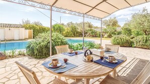A covered outdoor dining area with a pool and lush greenery in the background. - Amazing home in Chiaramonte Gulfi RG (Chiaramonte Gulfi RG)