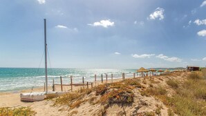 A beach with a thatched-roof structure, a flagpole, and a small building. - Amazing home in Chiaramonte Gulfi RG (Chiaramonte Gulfi RG)