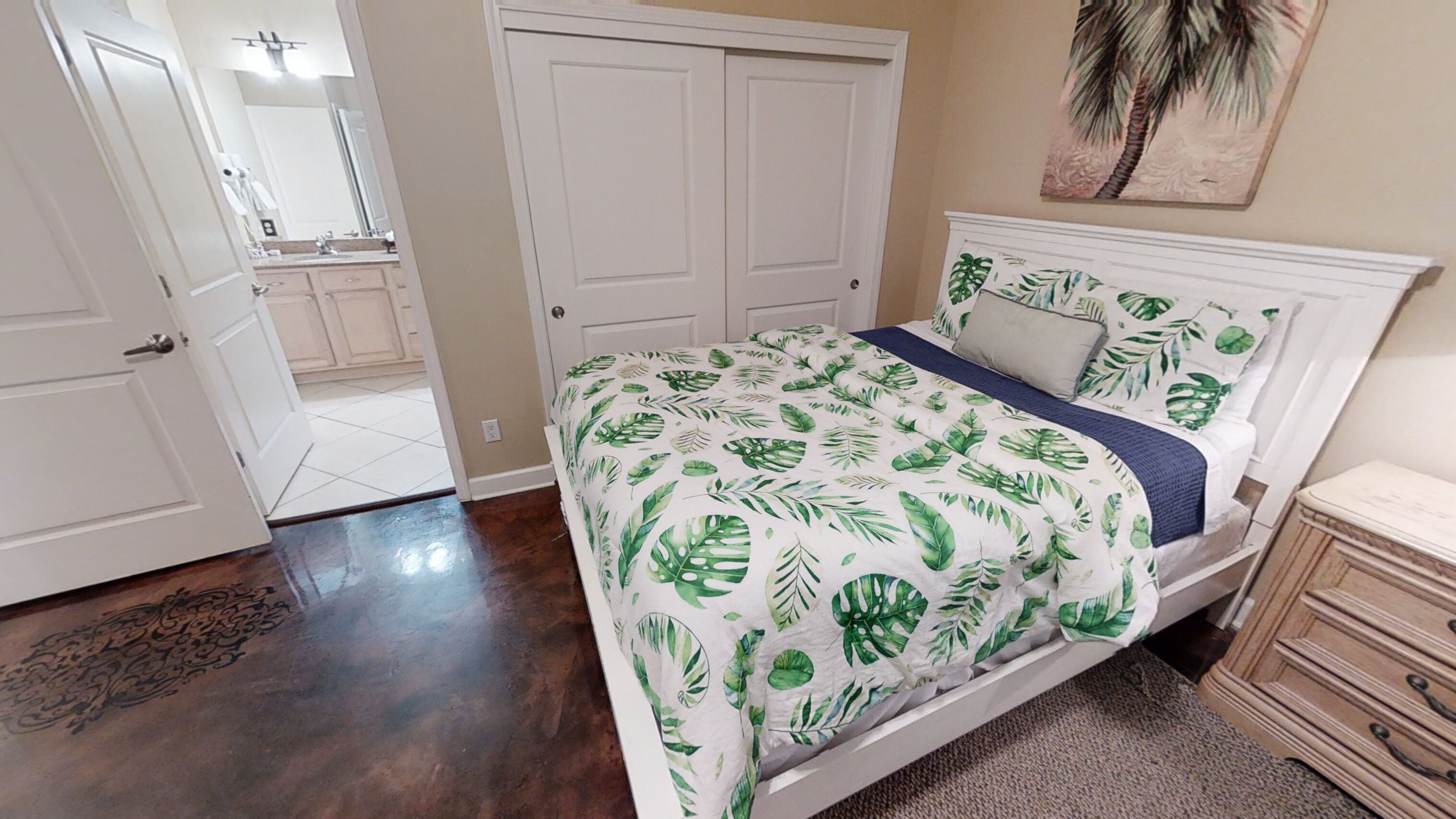 Un dormitorio con cama, mesita de noche, cómoda y puerta que da a un baño.