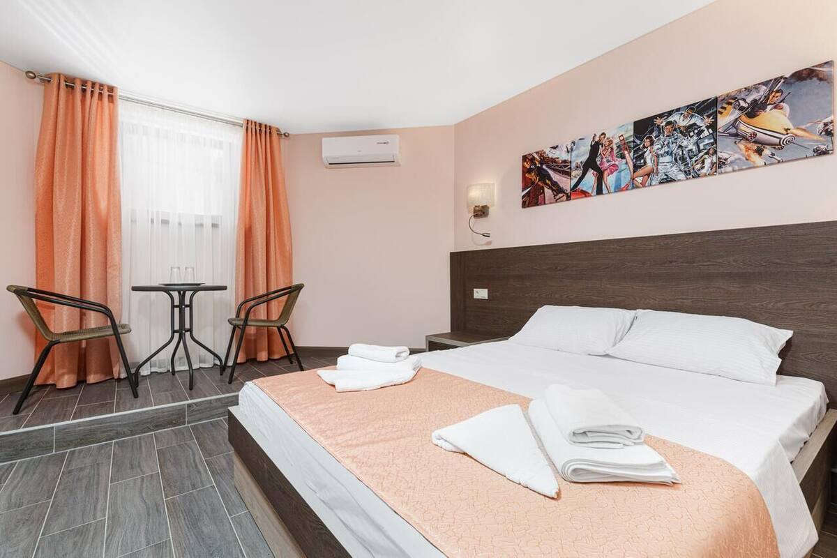 Habitación de hotel con una cama grande, dos sillas, una mesita y aire acondicionado instalado en la pared.