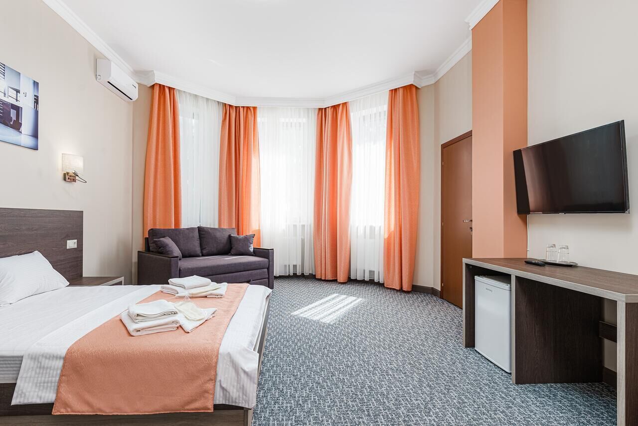 Una habitación de hotel con cama, escritorio, televisor y sofá.