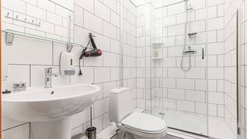 Un baño moderno con lavamanos, inodoro y cabina de ducha de vidrio.