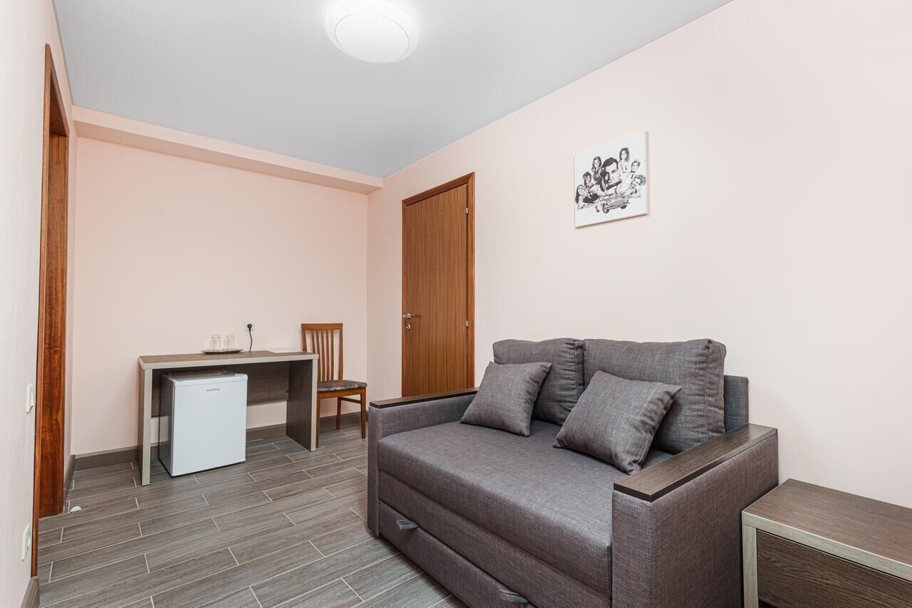 A compact living space with a sofa, a small table, a chair, and a refrigerator.