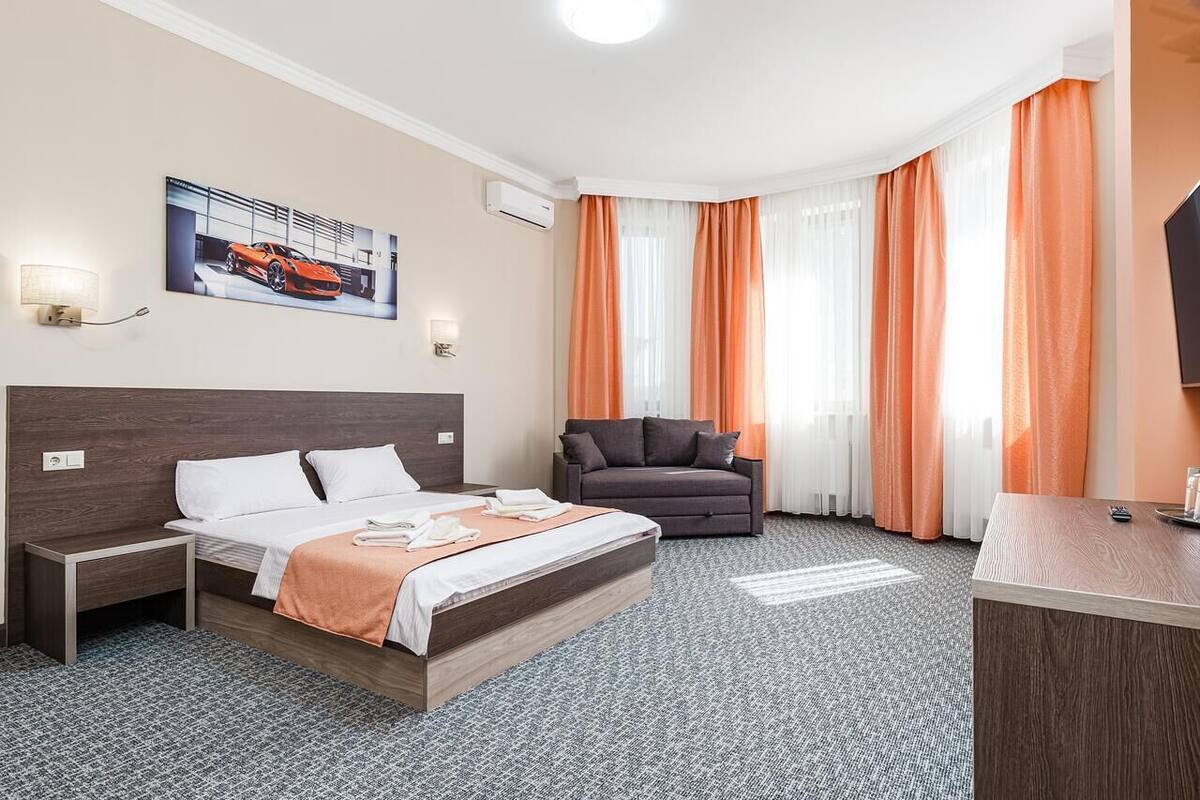Una habitación de hotel con cama, escritorio, sofá y un cuadro en la pared.