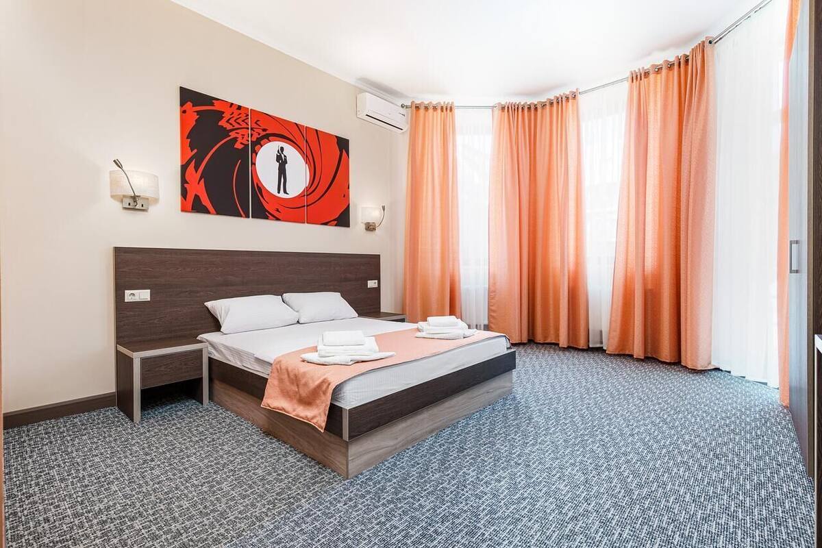 Habitación de hotel con una cama grande, una mesita de noche, una lámpara de pared y un cuadro.