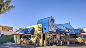 Ein Restaurant mit Außenbereich, einer blauen Markise und einem Schild, das Meeresfrüchte, Pizza und Pasta anbietet.