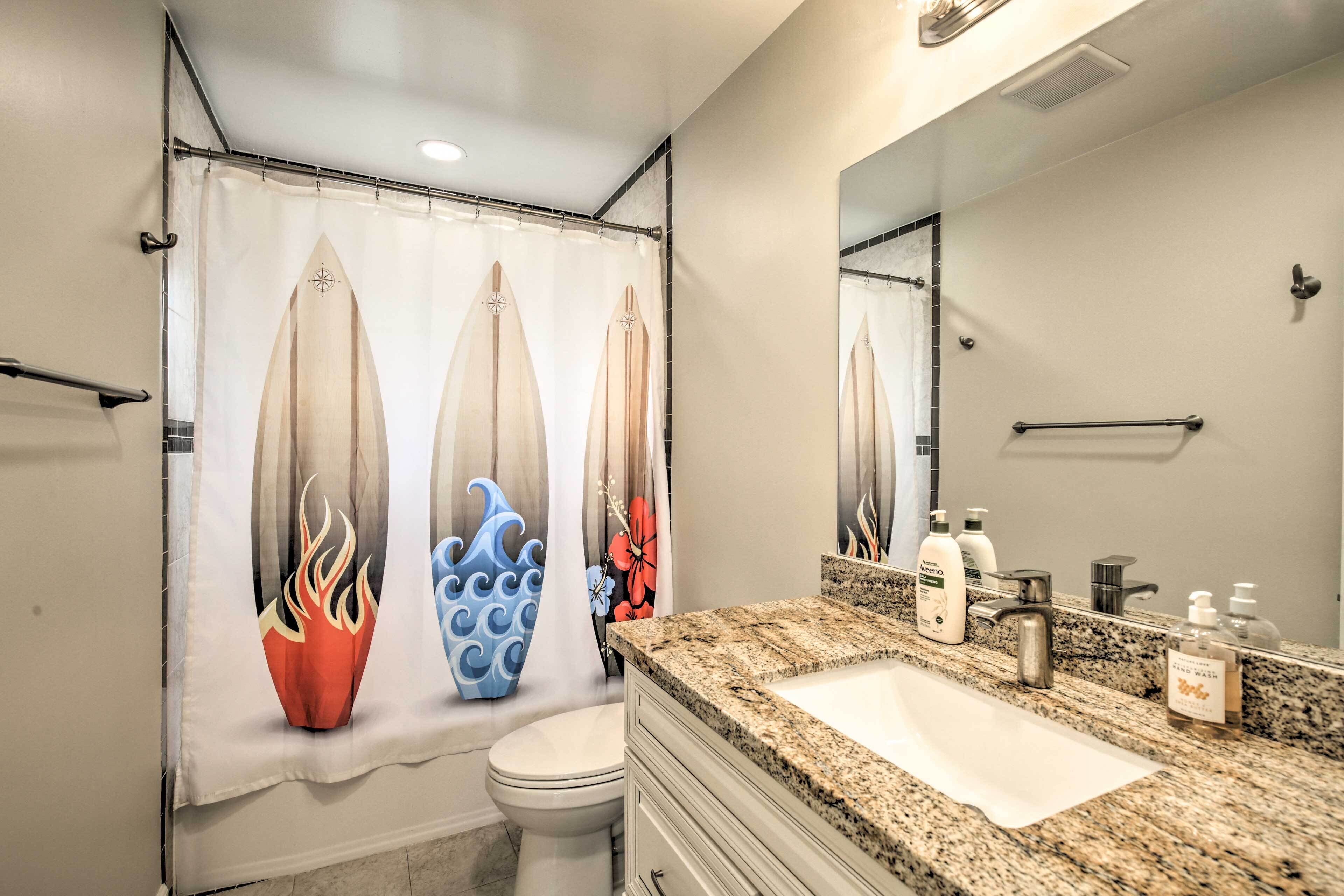 A bathroom with a shower curtain featuring surfboard designs, a white sink, and a mirror above it.