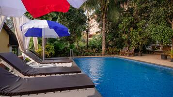 A poolside area with lounge chairs and umbrellas.