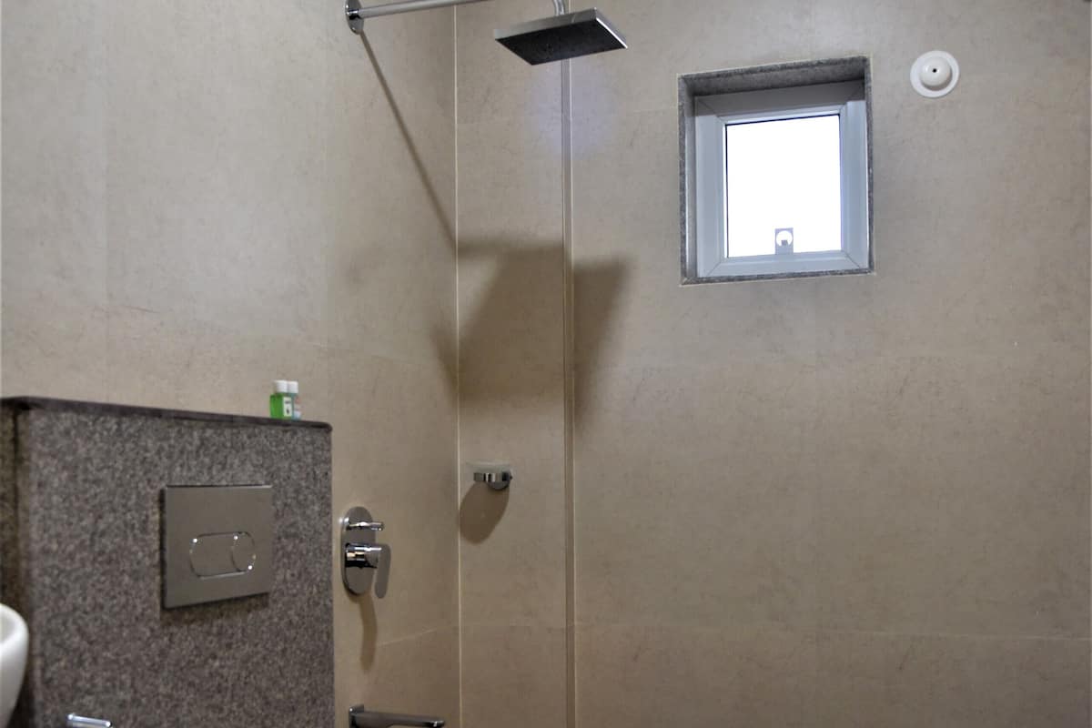 A bathroom with a toilet, a shower, and a small window.