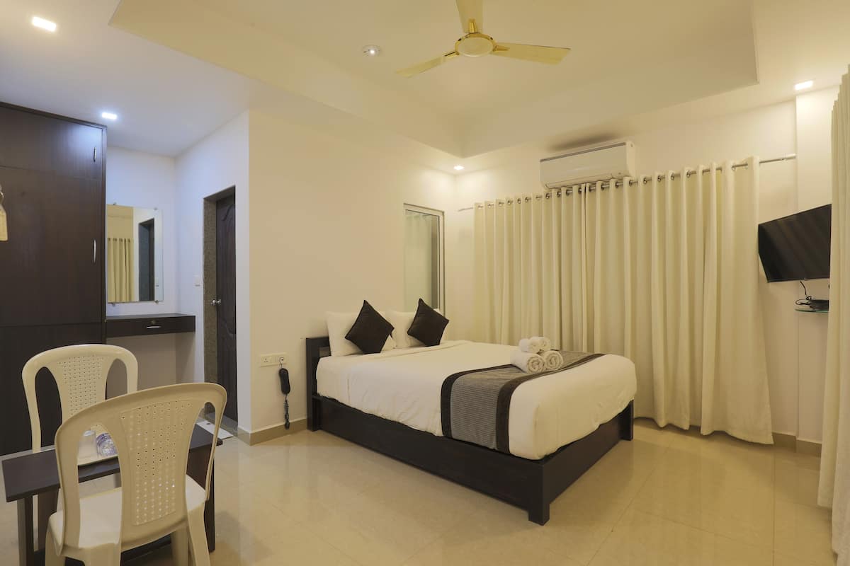 A hotel room with a bed, a desk, a chair, a ceiling fan, and curtains.