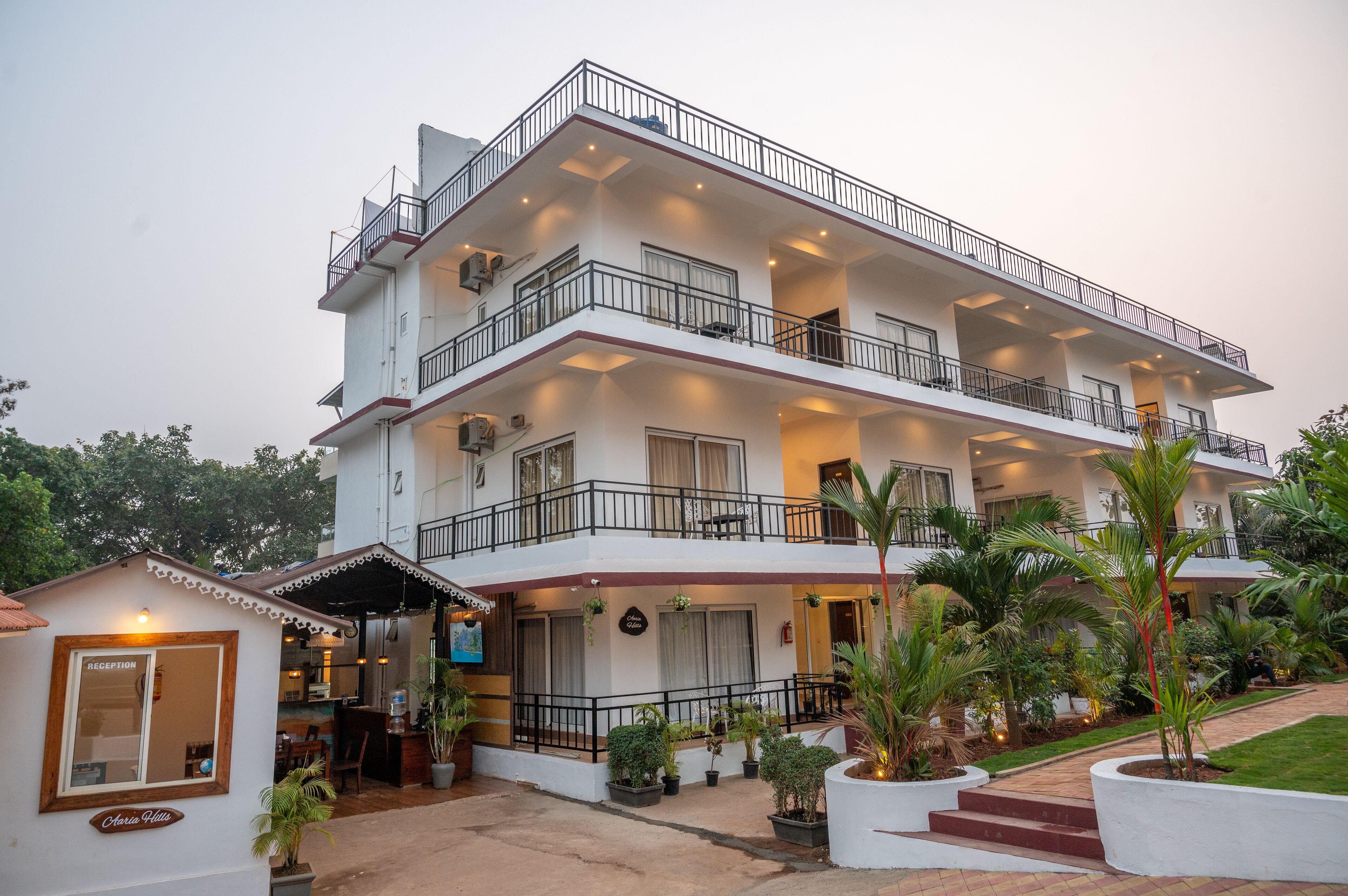 A multi-story hotel with a reception area, balconies, and potted plants.