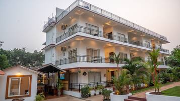A multi-story hotel with a reception area, balconies, and potted plants.