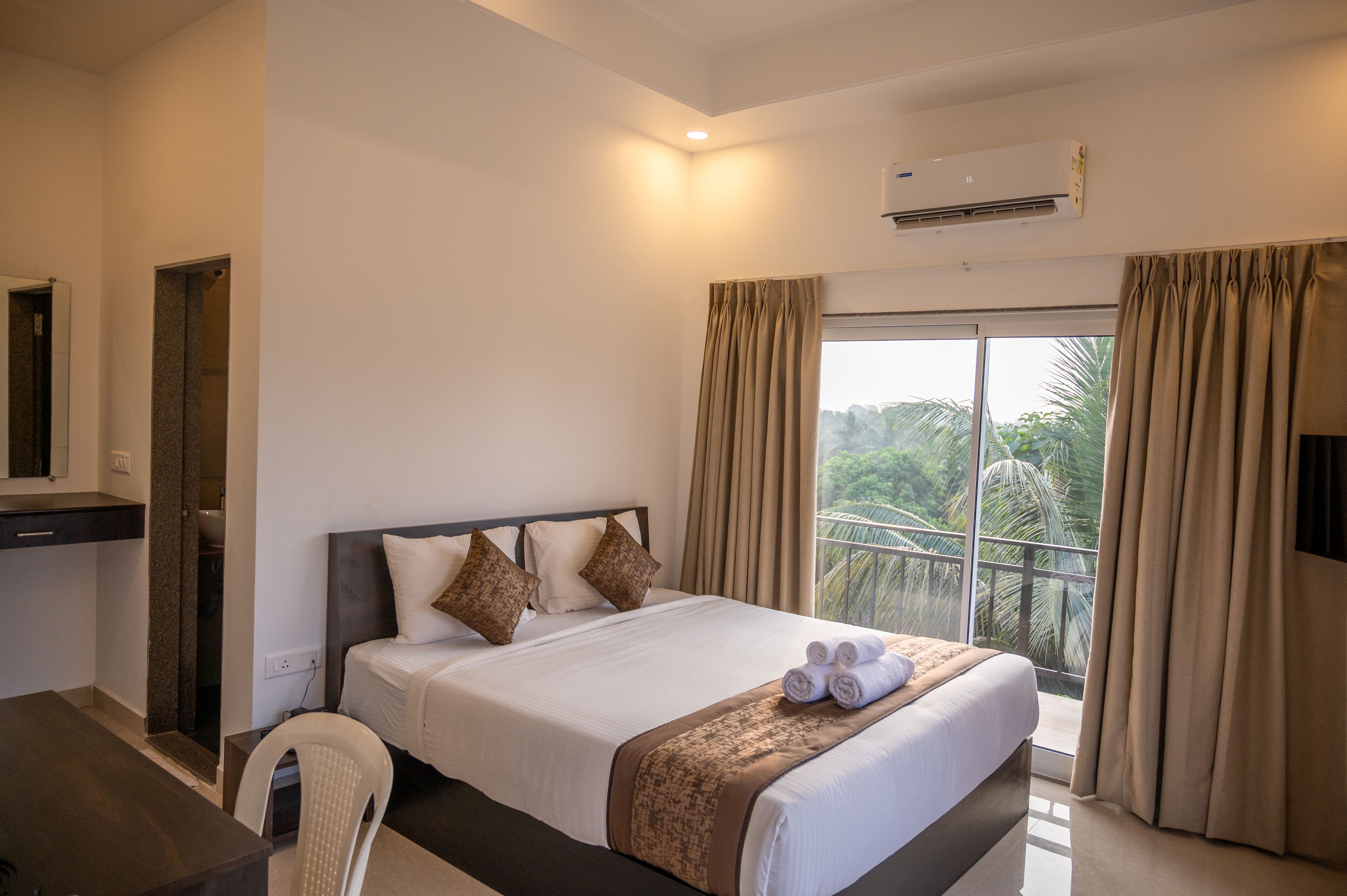 A hotel room with a bed, a desk, and a view of the outdoors.