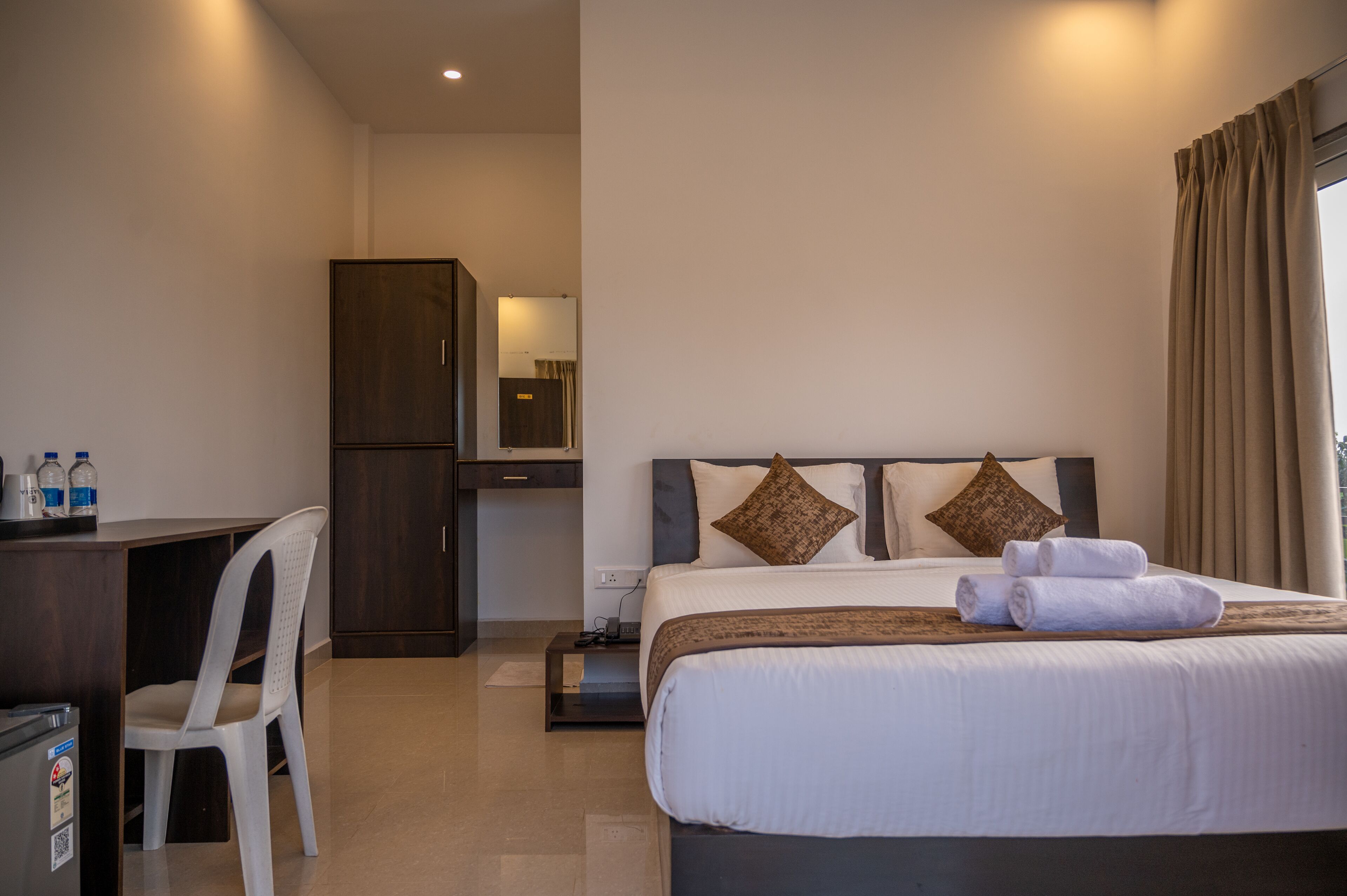 Hotelkamer met een bed, een bureau, een stoel, een kledingkast en een badkamer op de achtergrond.