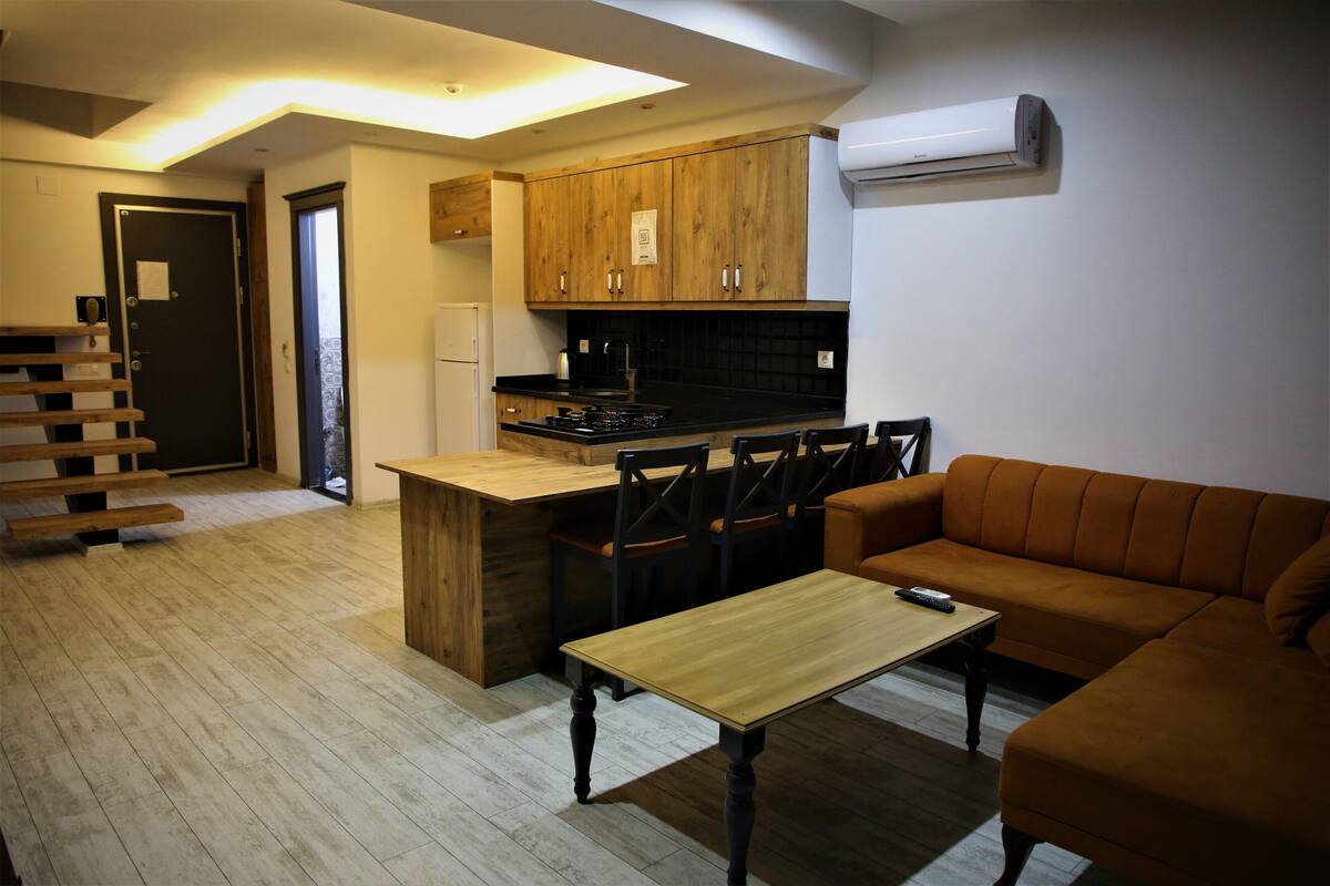 Um espaço compacto com cozinha americana, área de jantar e sofá.