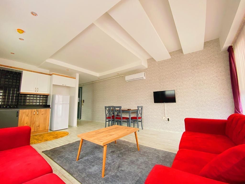 A modern living room with red sofas, a wooden coffee table, and a TV mounted on the wall.