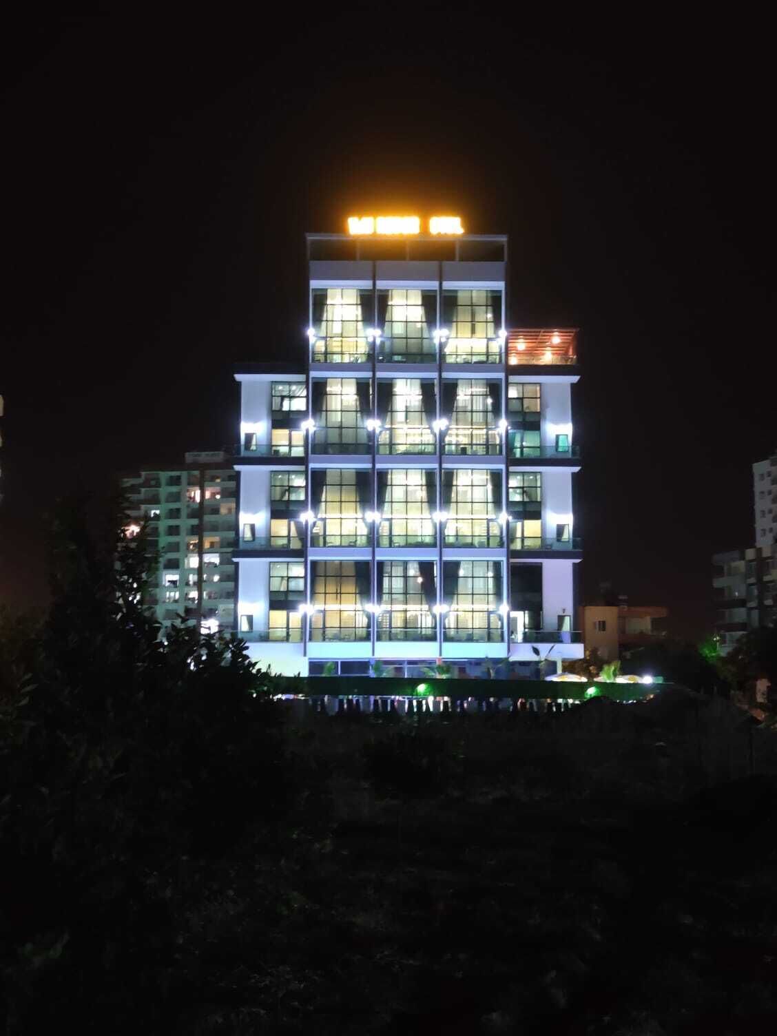 Een meerhoog gebouw met verlichte ramen en een opvallend bord bovenaan.