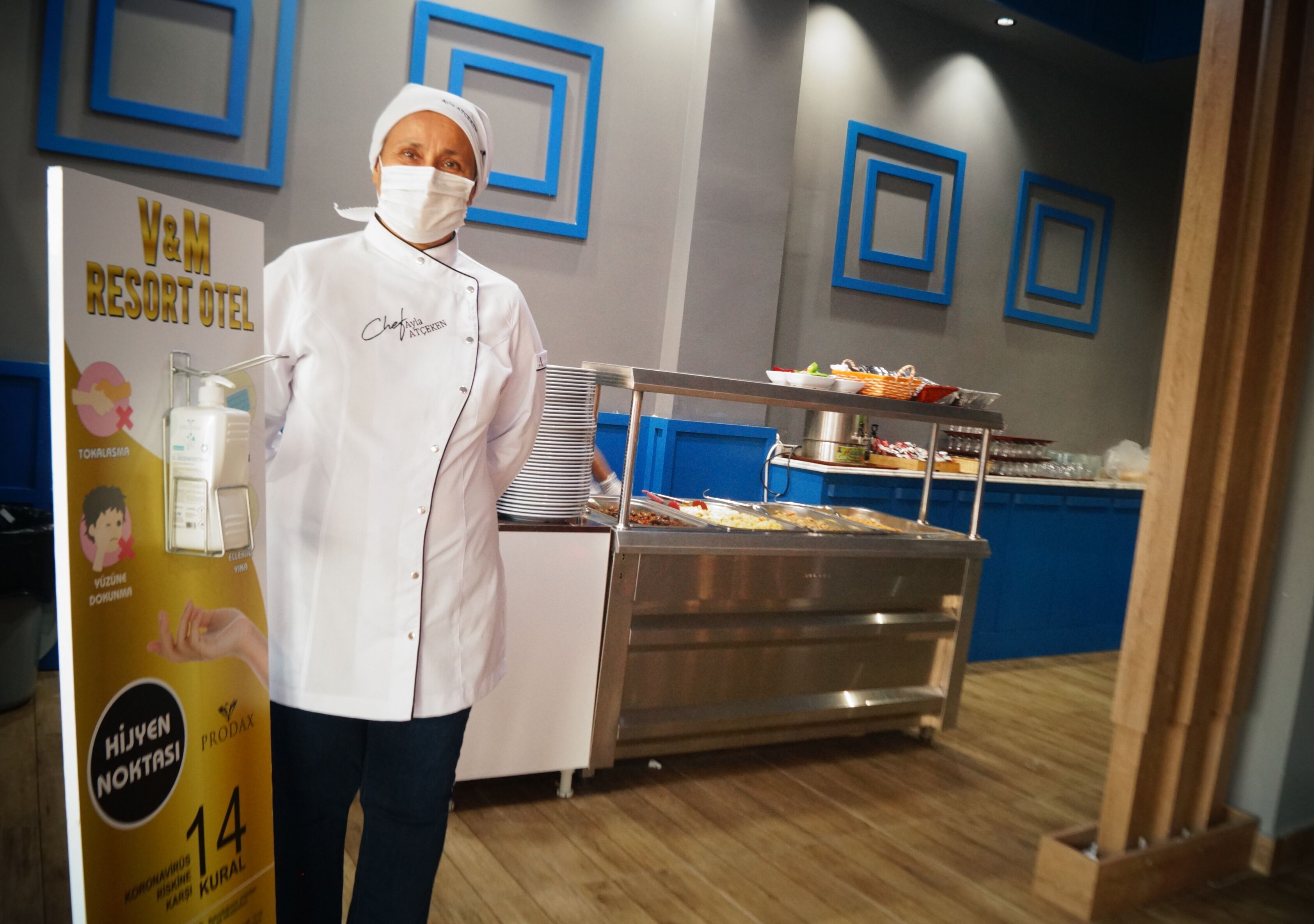 A buffet setup with a variety of food items and a person in a chef's uniform.