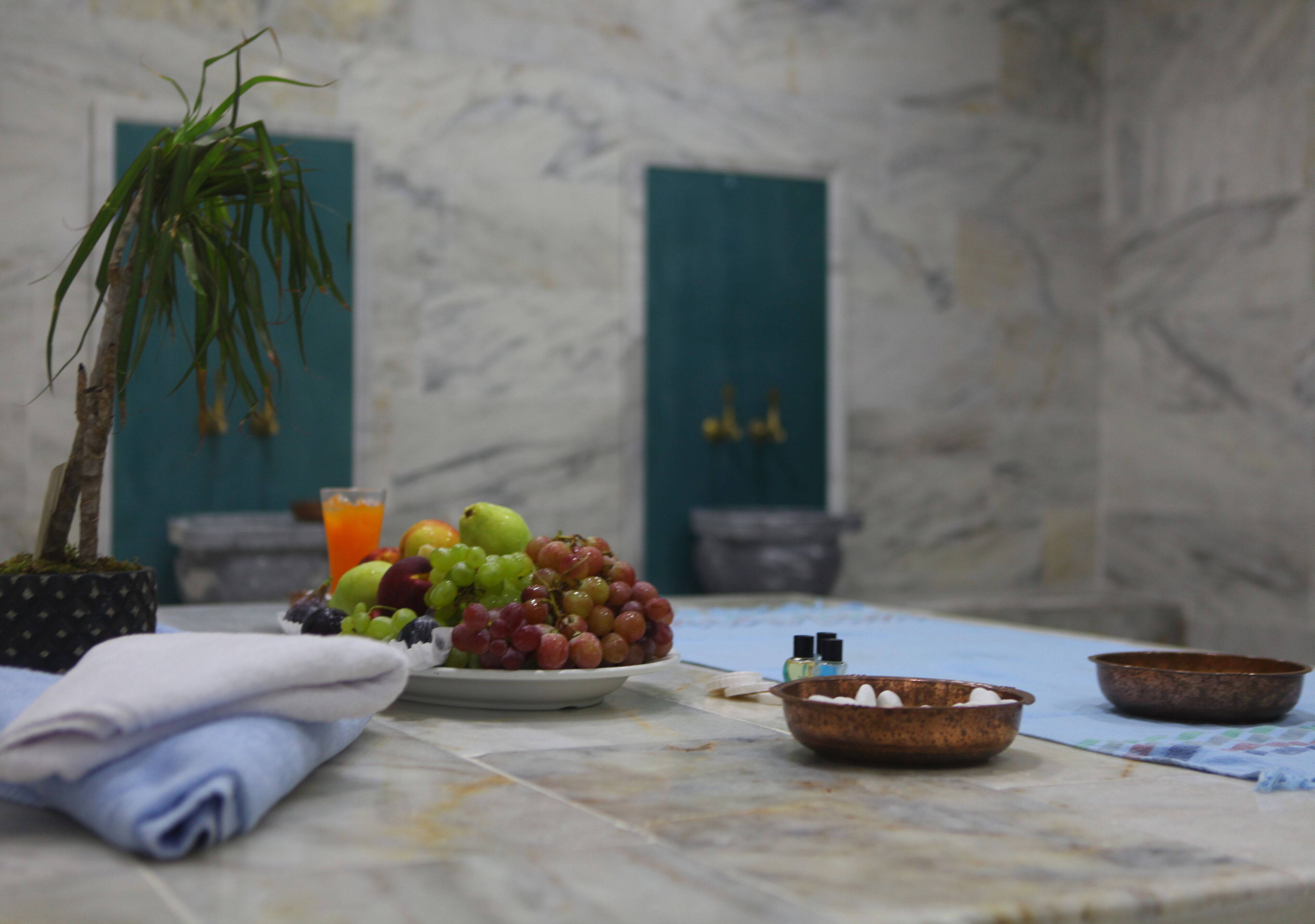 A marble-tiled table with a fruit plate, a small potted plant, and a bowl of sugar.