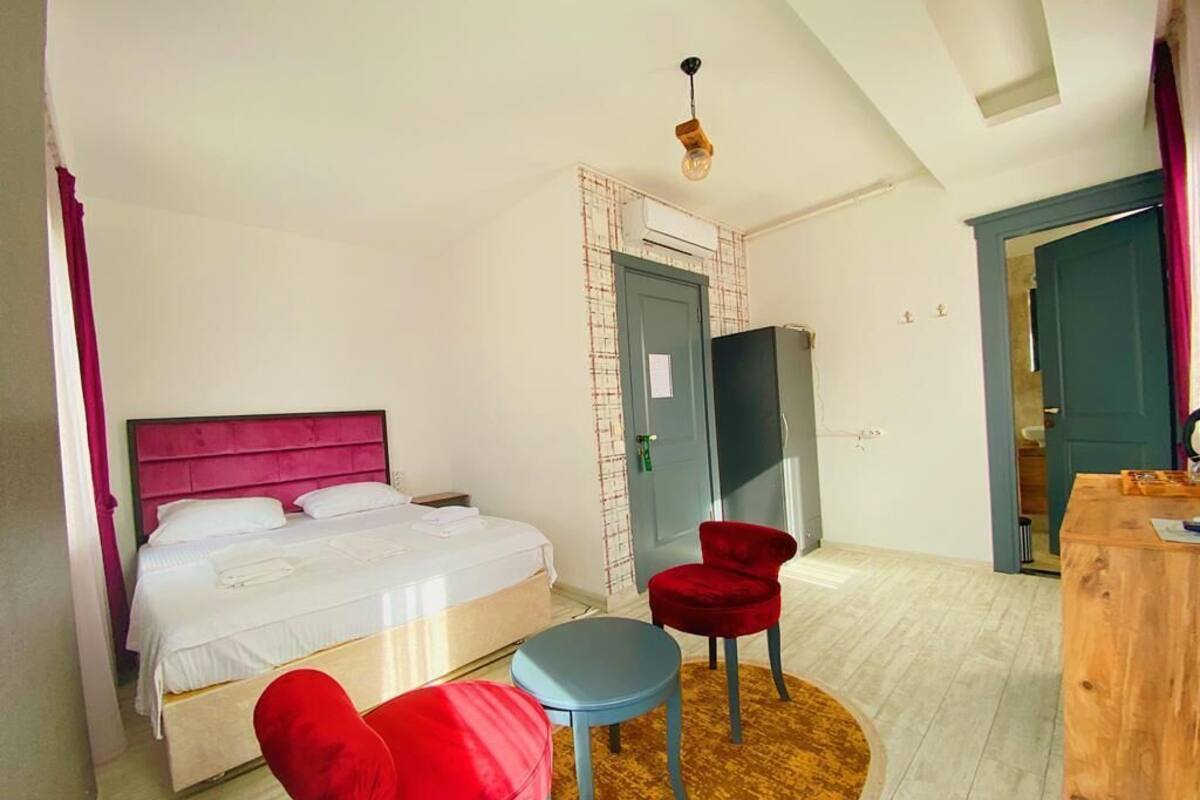 Quarto com cama, escrivaninha e duas cadeiras.