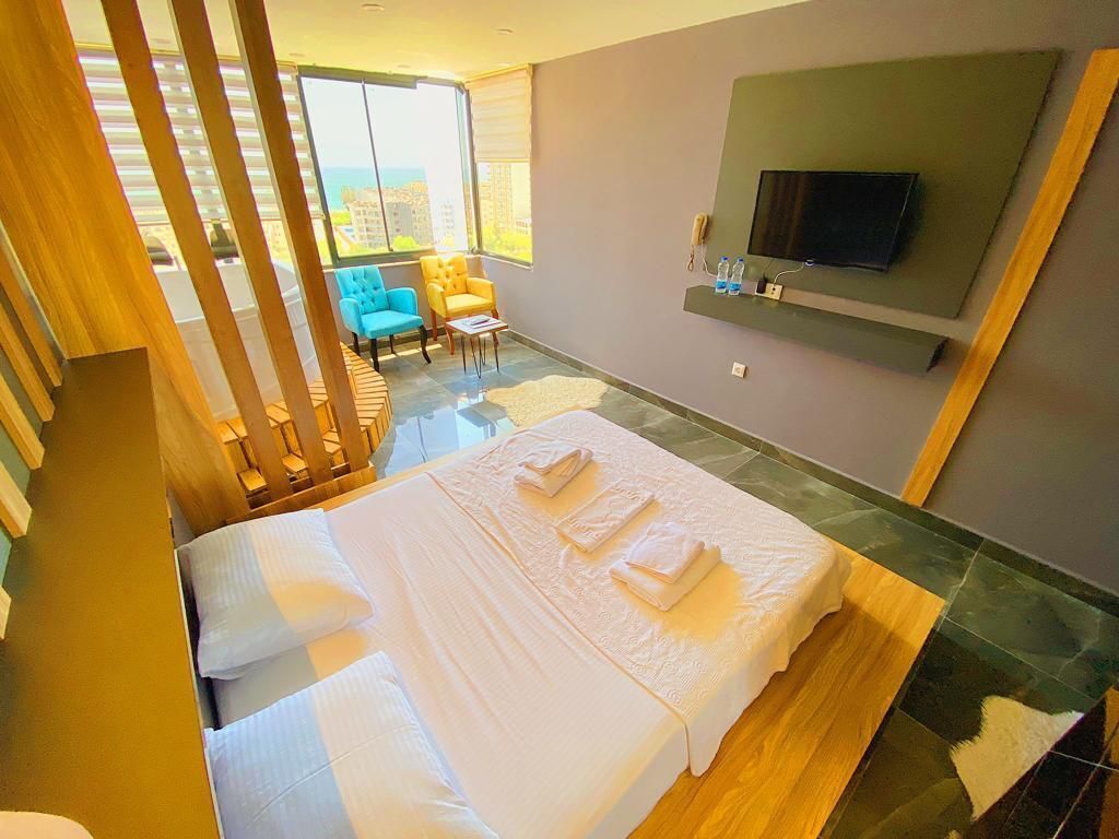 Habitación de hotel con cama, televisión montada en la pared y balcón con vista a la ciudad.