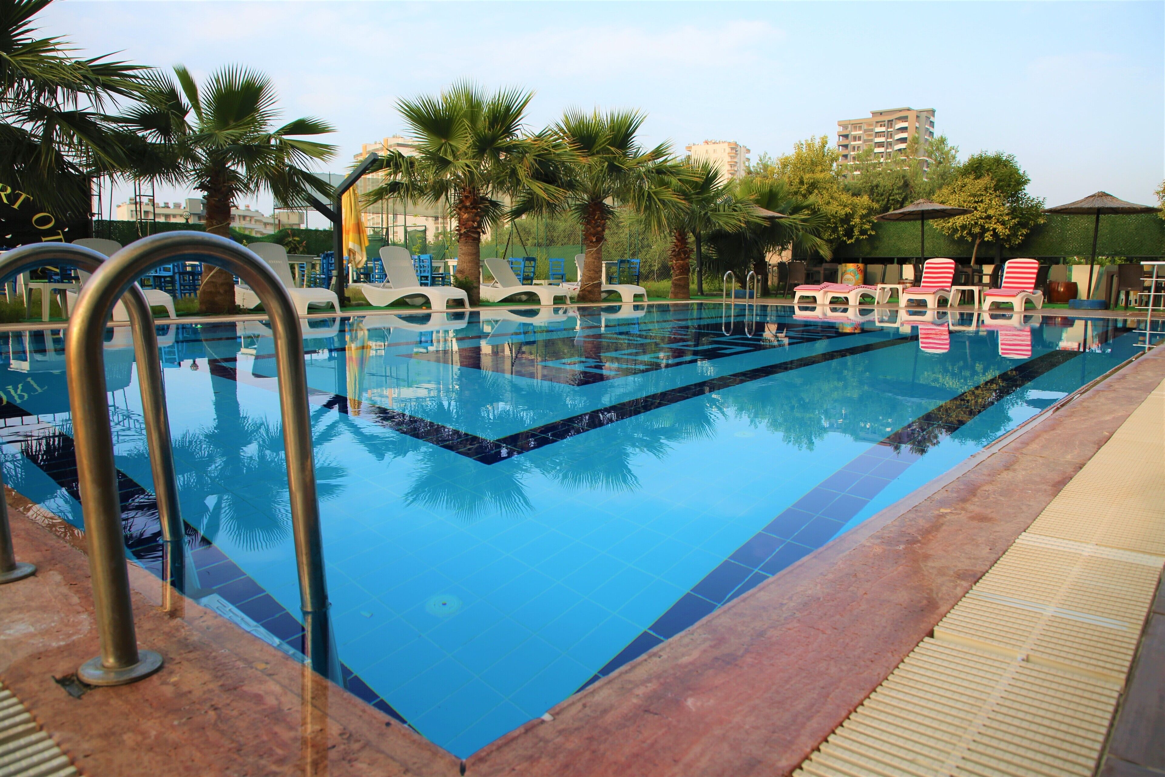 Una piscina con sillas de descanso y palmeras.
