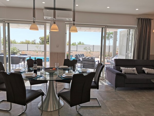 A dining area with a glass table, black chairs, and a sofa.