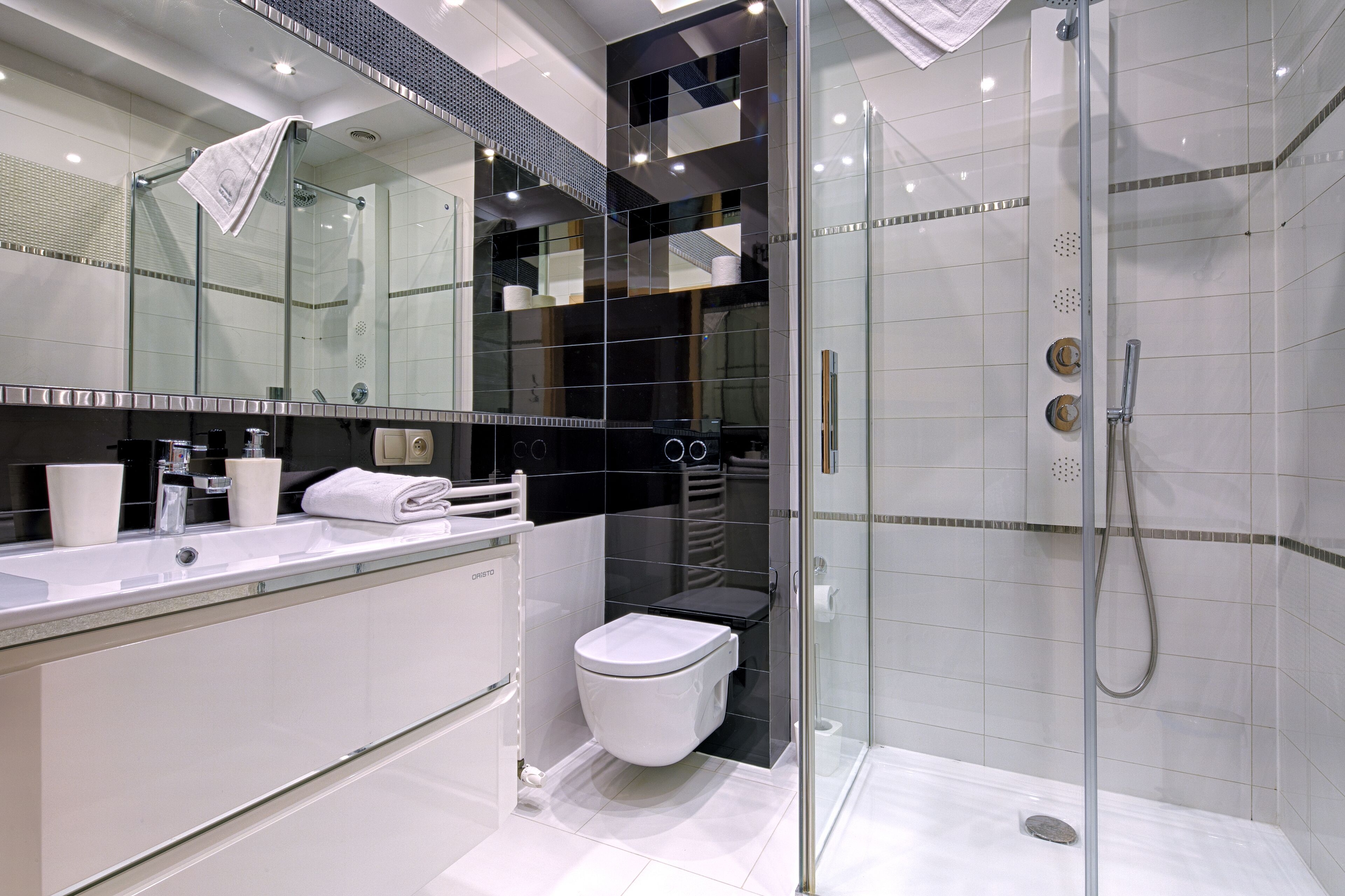 A modern bathroom with a glass-enclosed shower, a white toilet, and a large mirror above the sink.