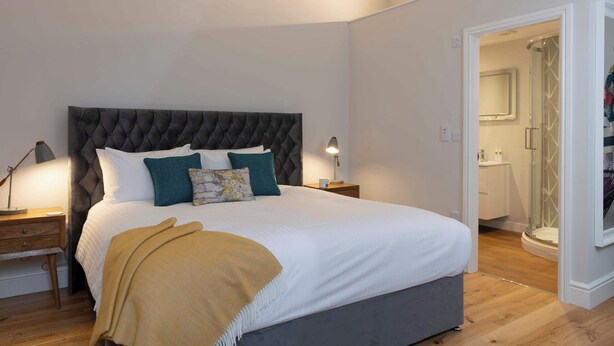 Een slaapkamer met een groot bed, nachtkastjes, een nachtkast en een inloopkast.