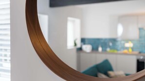 Een moderne keuken met een blauwe achterwand, witte kastjes en een zichtbaar raam.